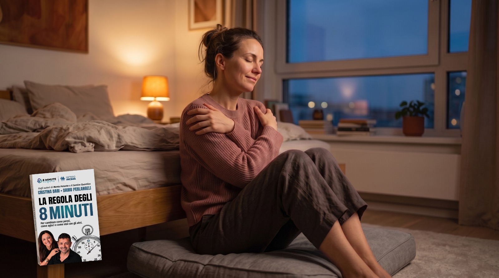 Donna seduta sul pavimento della camera da letto al tramonto, occhi chiusi e mani incrociate sul petto, con il libro La Regola degli 8 Minuti in primo piano